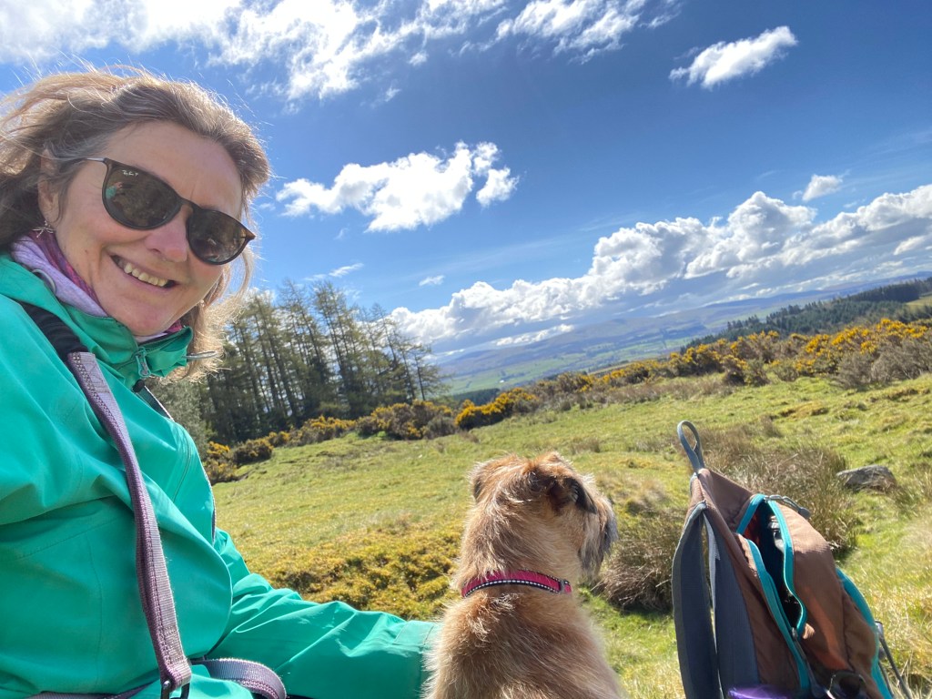Picture of Jo, in the countryside with her dog.
